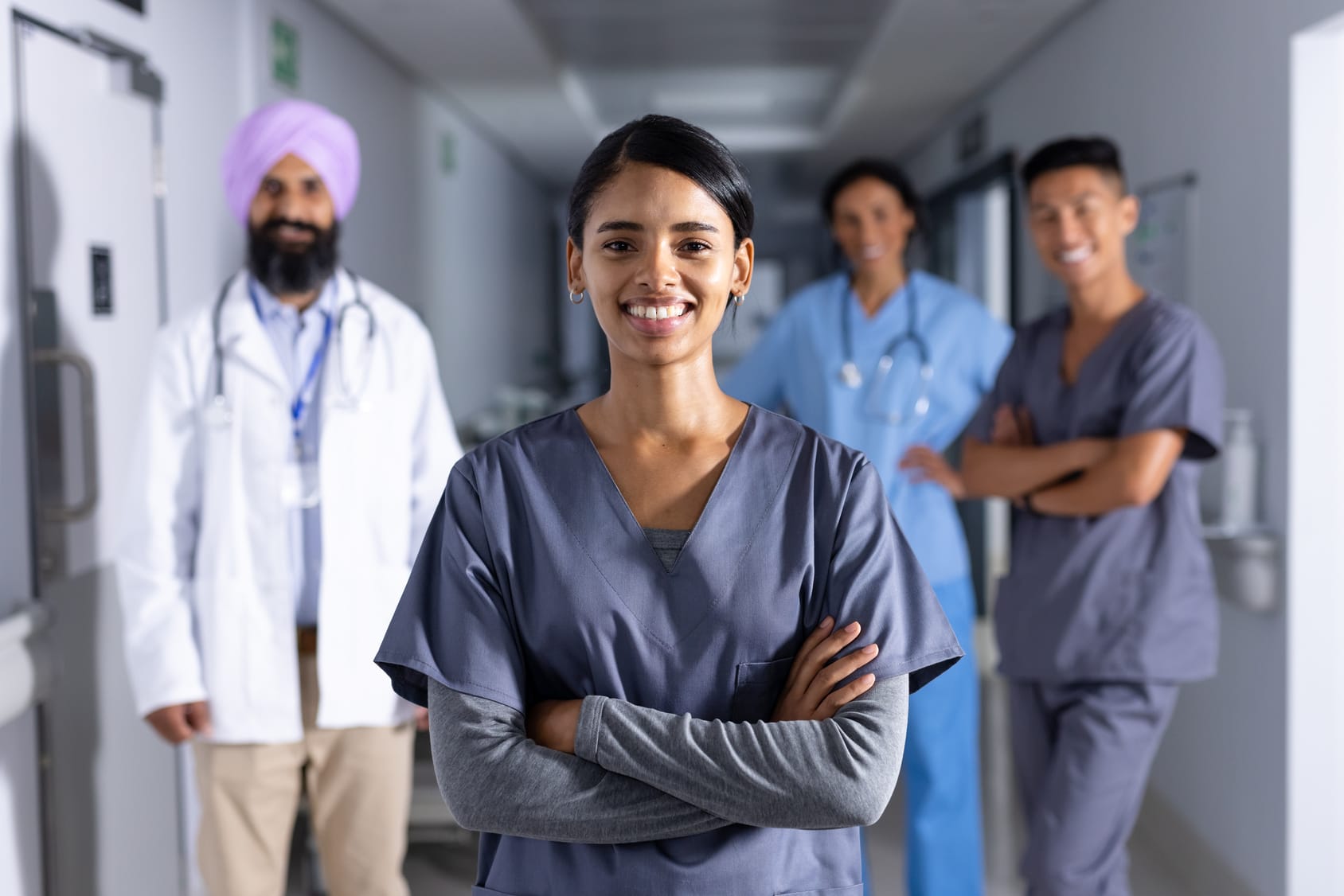 Group portrait of happy diverse male and female doctors standing in corridor at hospital